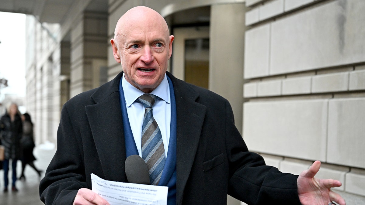 Mark Kelly addresses reporters while standing outdoors near the courthouse.