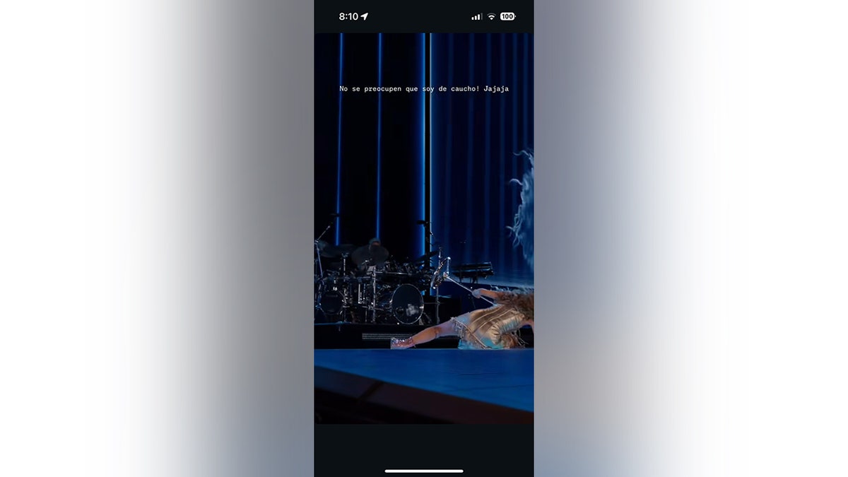 Shakira laying on floor of stage holding mic stand