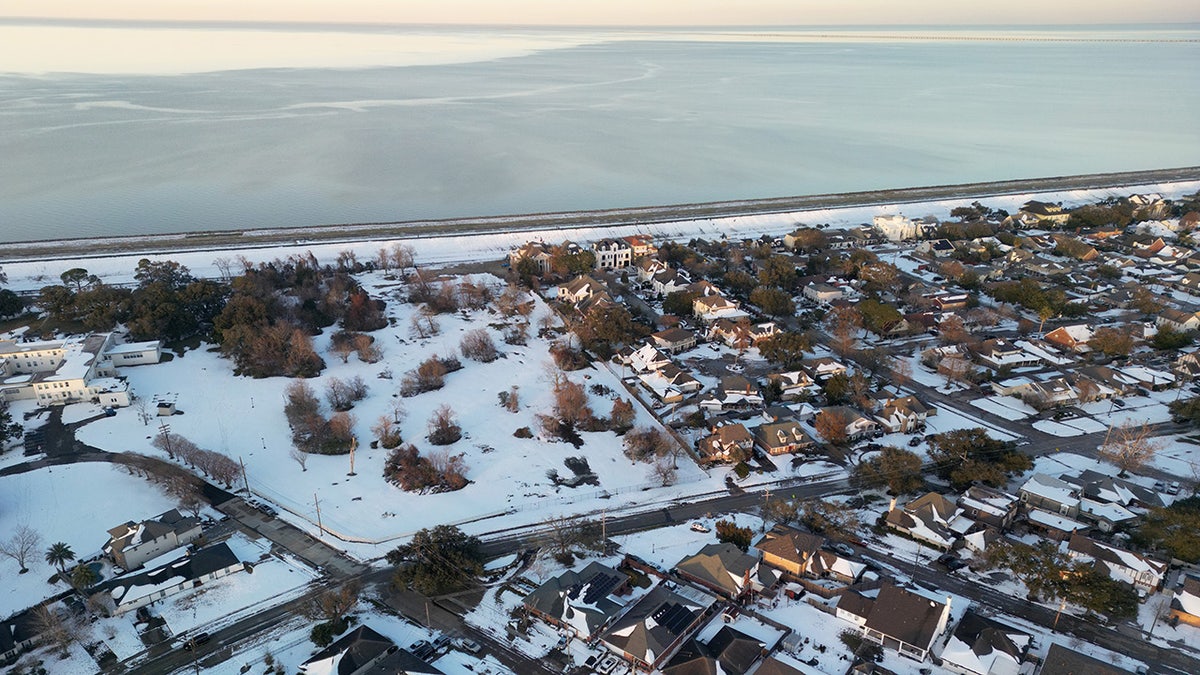 Aerial view of snow-covered homes in Metairie, Louisiana, near Lake Pontchartrain during a rare winter snowstorm.
