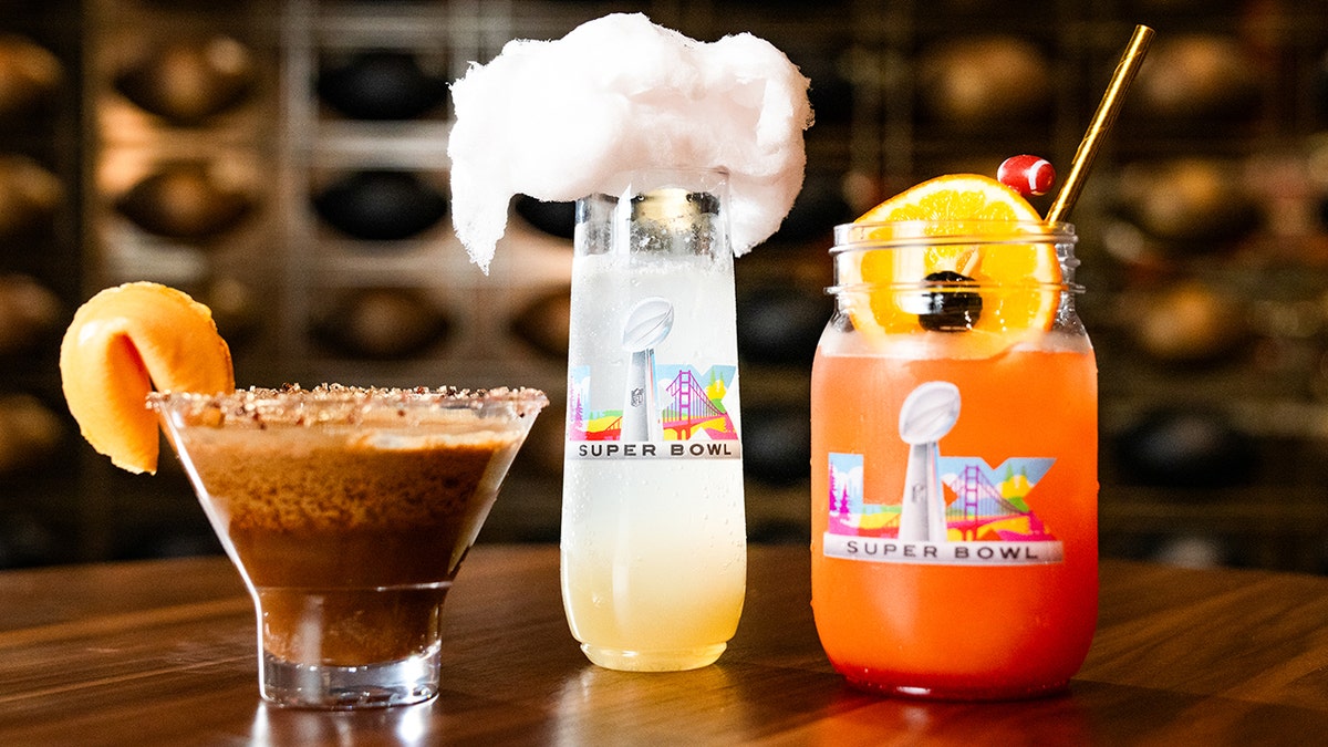 Three fancy craft cocktails being offered at the Super Bowl, seen topped with garnishes and in branded drinkware.