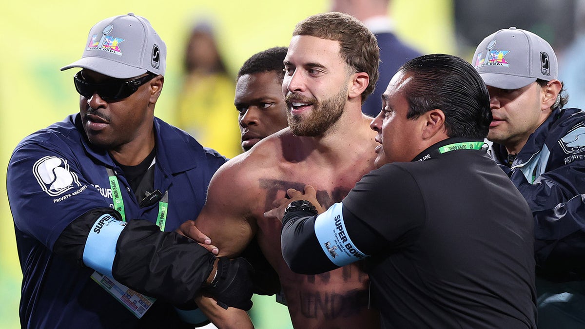 A fan is escorted off the field
