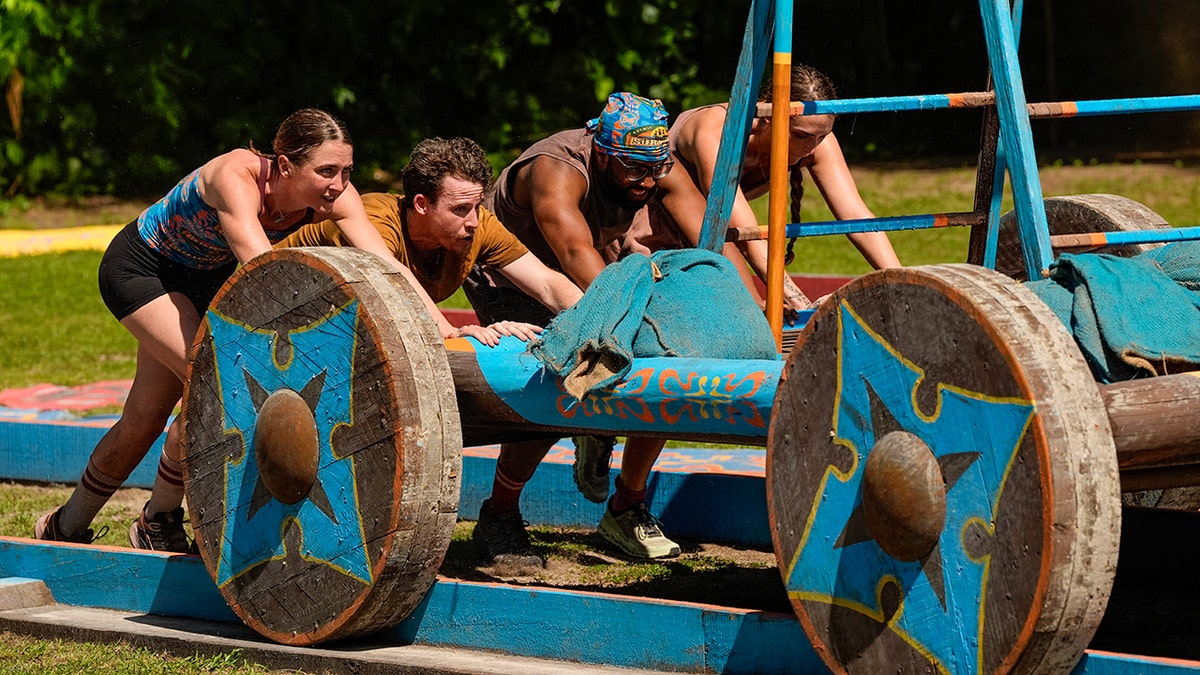 The surviving contestants push a wheel as part of the challenge in October 2025.