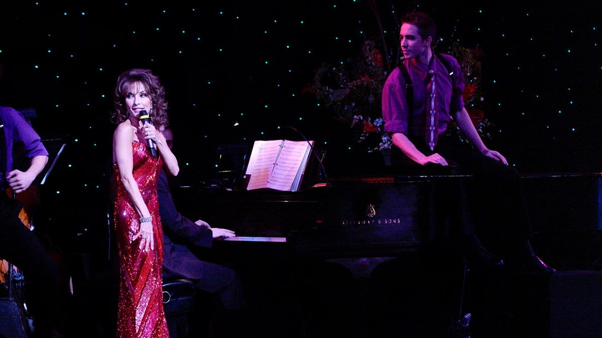 Susan Lucci wearing a red dress and performing on stage.