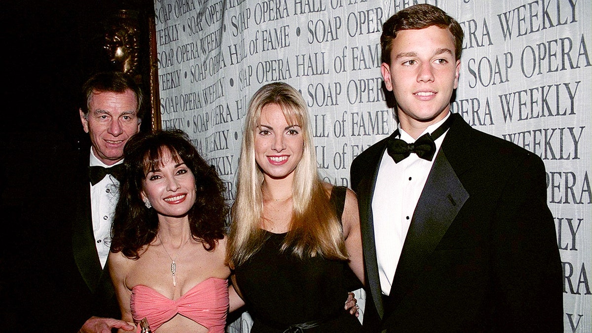 Susan Lucci in a pink cut-out dress, posing with her family.