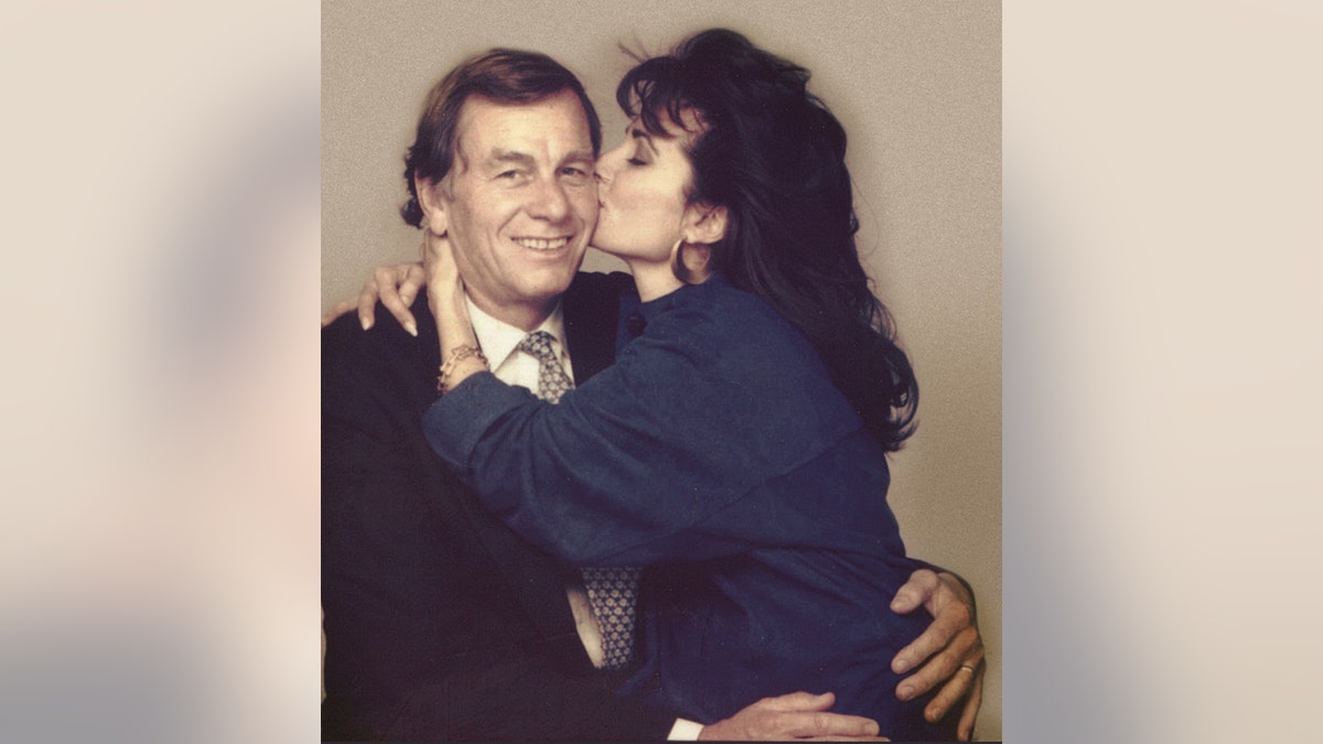 Susan Lucci wearing a blue sweater kissing her smiling husband.