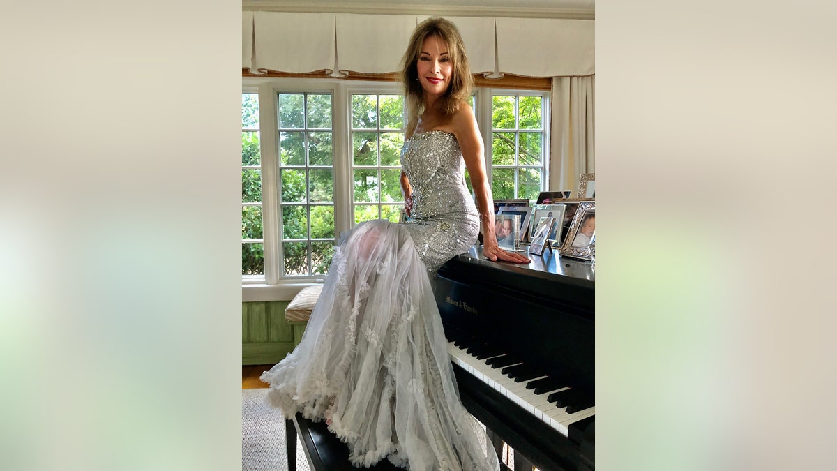 Susan Lucci sitting on top of a piano.