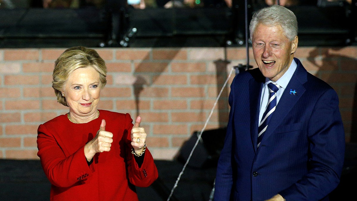 Democratic presidential candidate Hillary Clinton giving double thumbs up with Bill Clinton standing beside her at a rally