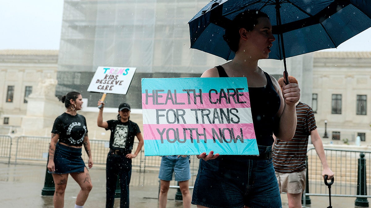 A protester holds a sign supporting gender-affirming care while standing outside the Supreme Court building.