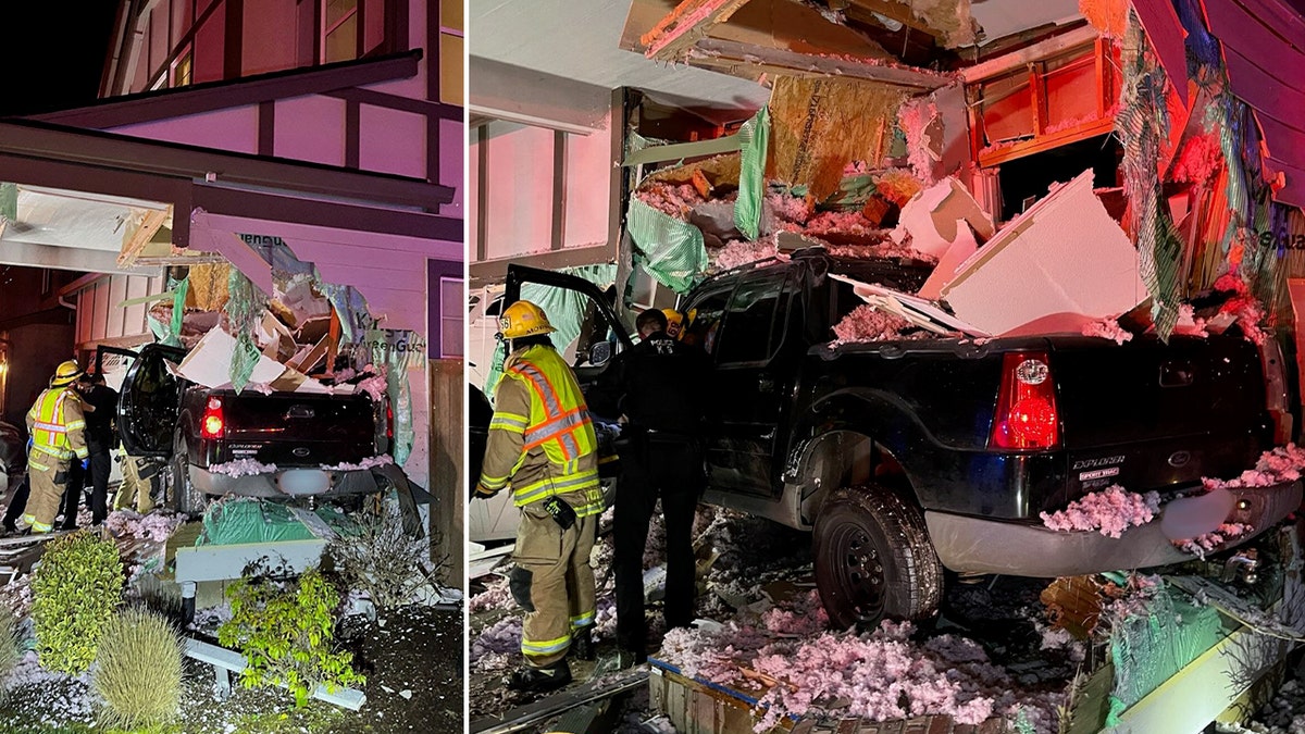 A crashed truck sticks out the side of a house.