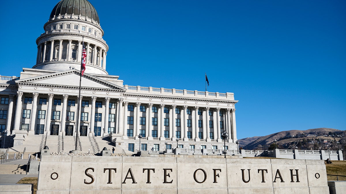 Flags are raised on poles outside a domed state government building.