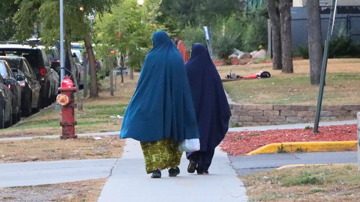 Two women wearing traditional Muslim clothing walk on a sidewalk in Minneapolis.