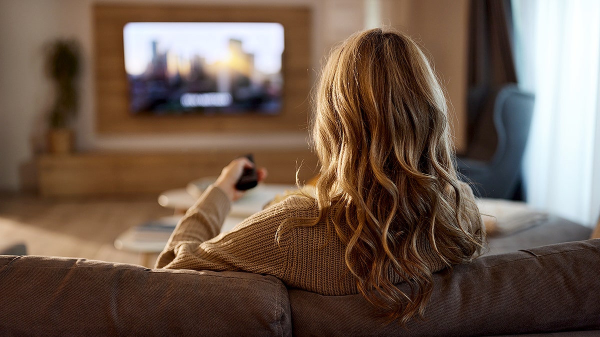 Woman watches TV on couch