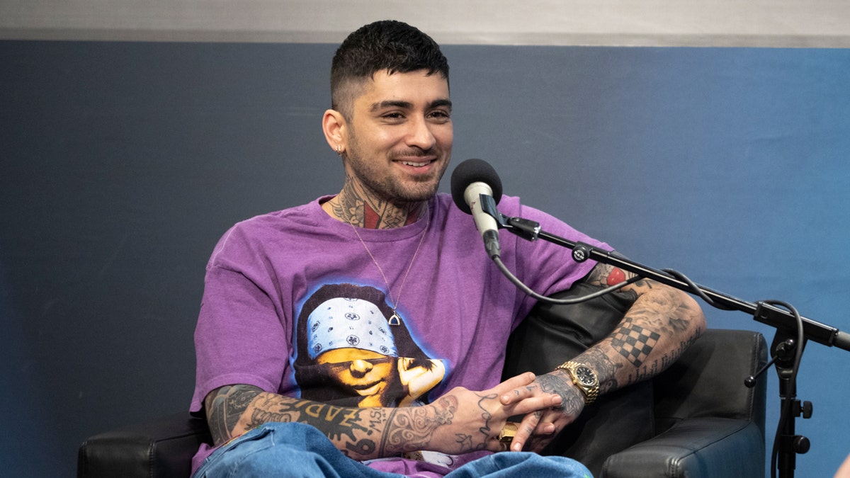 Zayn Malik and Melony Torres seated in a radio studio while speaking into microphones.