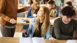 Student speaks with professor during classroom discussion.