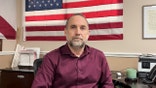 Eddie Speir sitting in front of an American flag