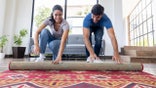 Couple unrolling a new carpet while moving home