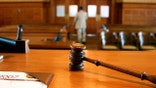 A gavel on a bench as people leave court