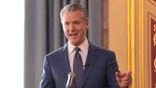 Gavin Newsom speaking at a microphone during a