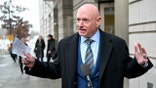 Mark Kelly answers questions from reporters near a courthouse entrance.