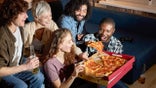 Friends sharing pizza while watching sports.