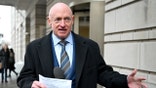Mark Kelly addresses reporters while standing outdoors near a courthouse.