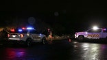 Two Pima County Sheriff's vehicles parked outside as a deputy collects orange cones