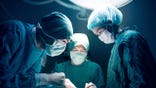 Surgeons are seen in an operation room performing a surgery.