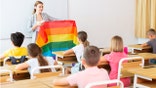 Teacher holding up pride flag in classroom