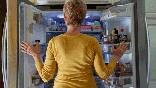 Woman looking for a snack in fridge - food cravings