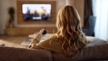Woman watches TV on couch