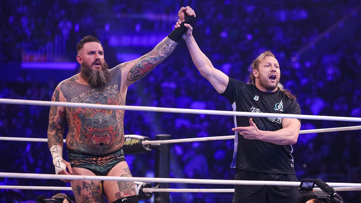 Kenny Omega raises the manus  of Brody King