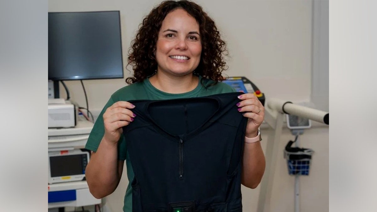A woman holding up a shirt
