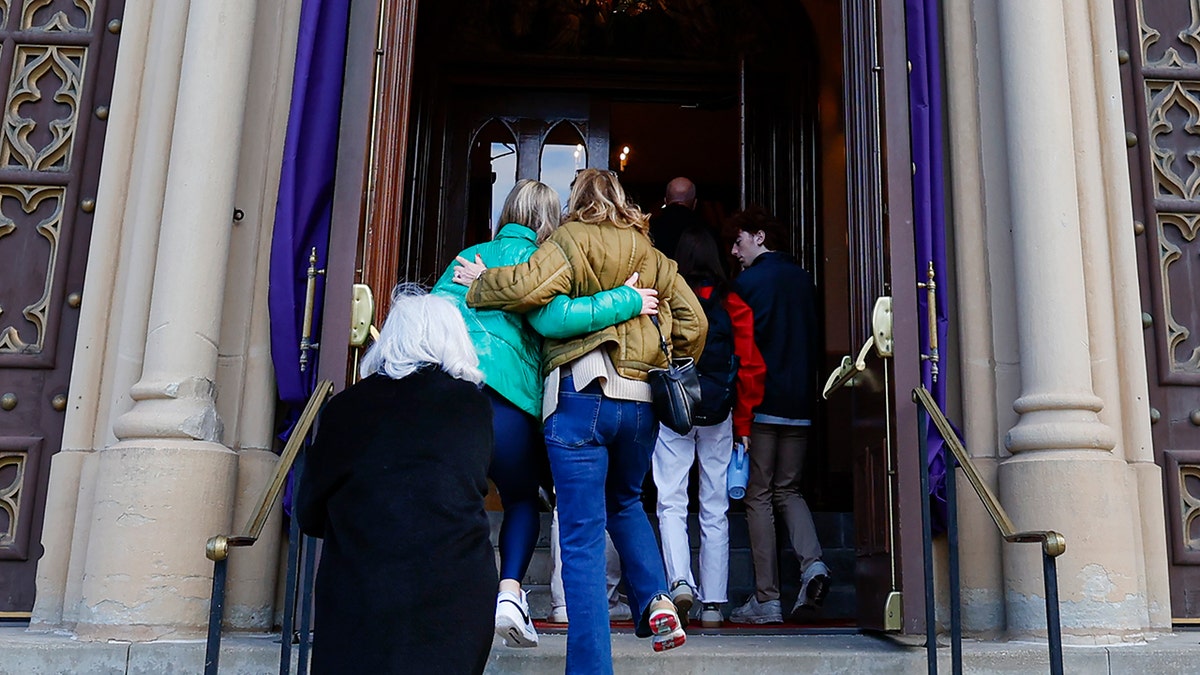 Mourners for Jimmy Gracey walk toward the entrance of the Church of the Holy Family in Chicago.