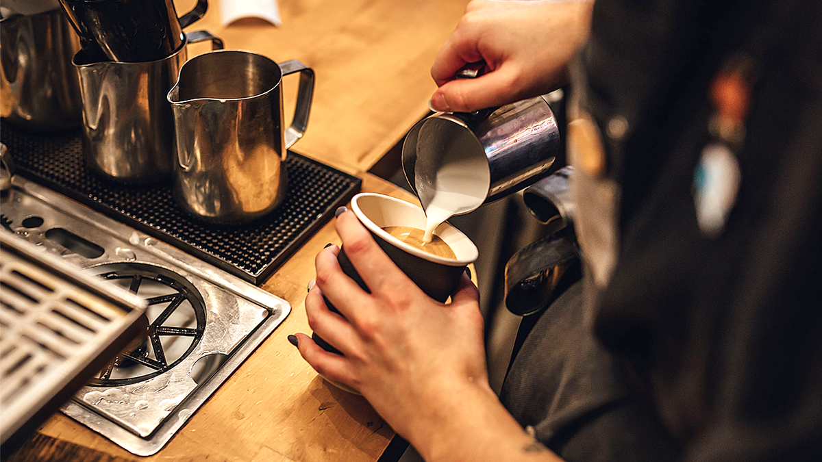 Barista pouring milk into cup