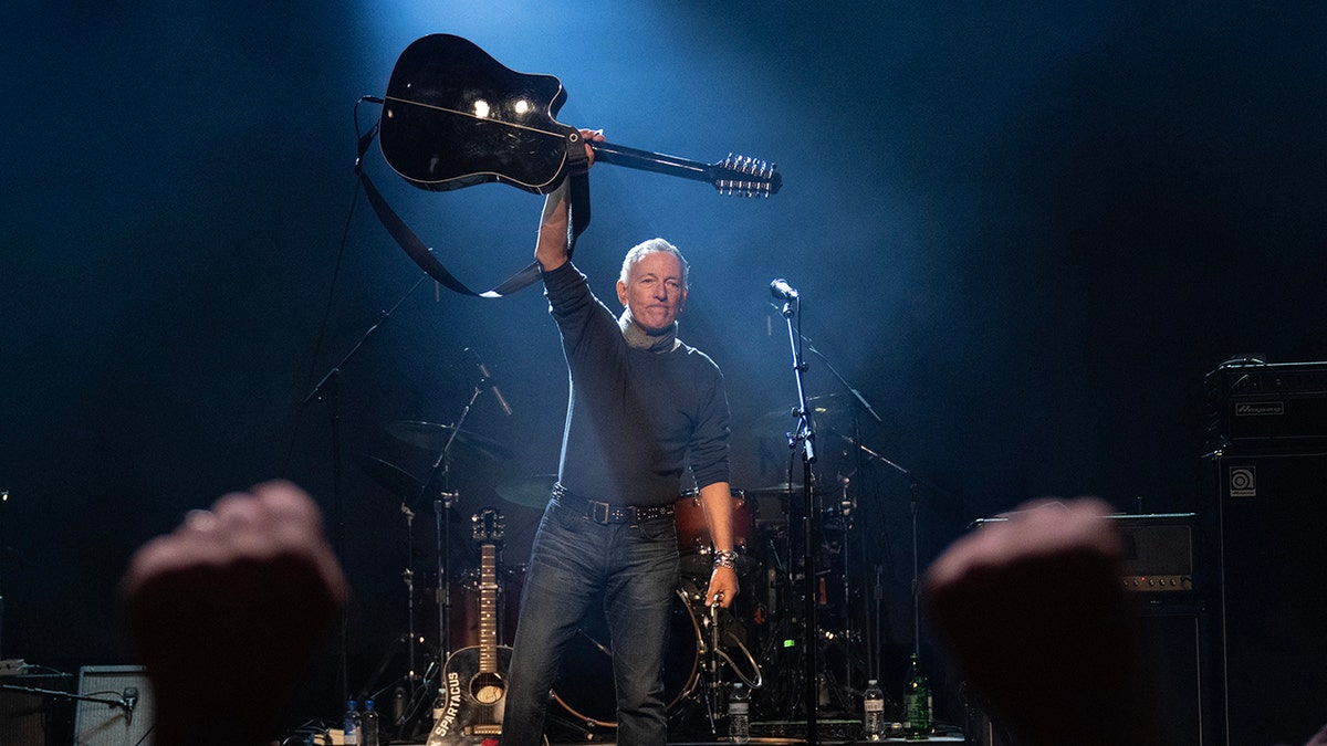 Bruce Springsteen holding his guitar above his head
