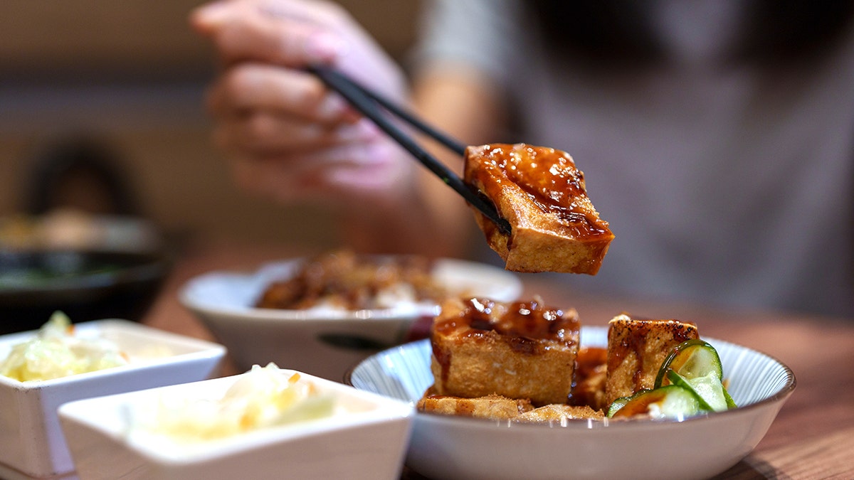 Woman holding stinky tofu with chopsticks