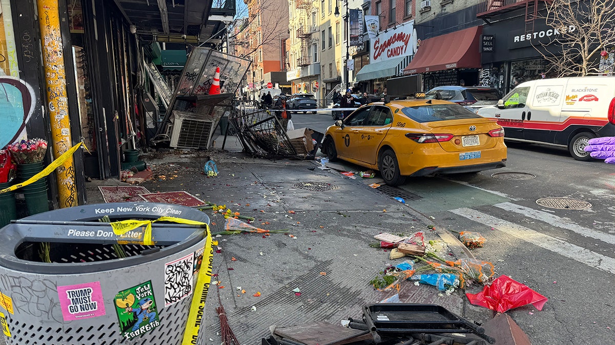 Yellow taxi sits amid debris aft Manhattan sidewalk crash.