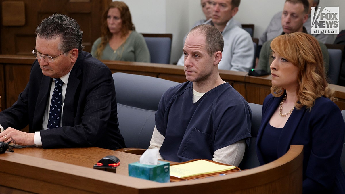 Caleb Flynn sitting at a table in a courtroom during a legal proceeding.
