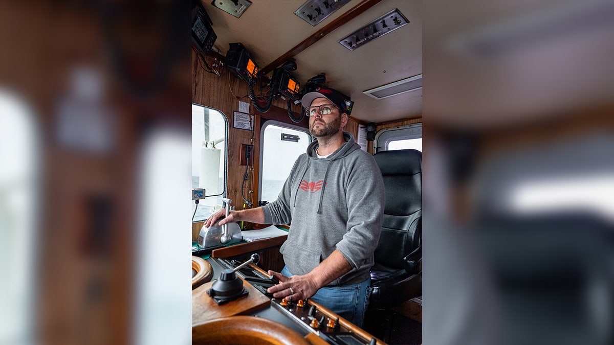 Captain Rick Shelford wears grey sweatshirt on boat.