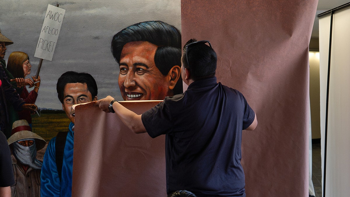 Un trabajador tapando un mural de Emigdio Vásquez que representa a César Chávez en el Santa Ana College.