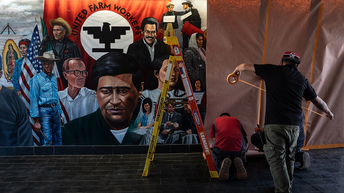 Workers covering a mural featuring Cesar Chavez at Santa Ana College