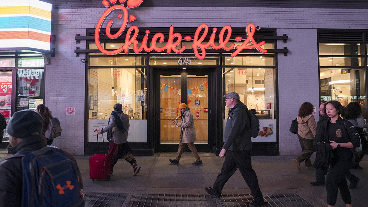A view of people walking in front of a Chick-fil-A restaurant with illuminated signage at night in Times Square on March 04, 2025 in New York City.