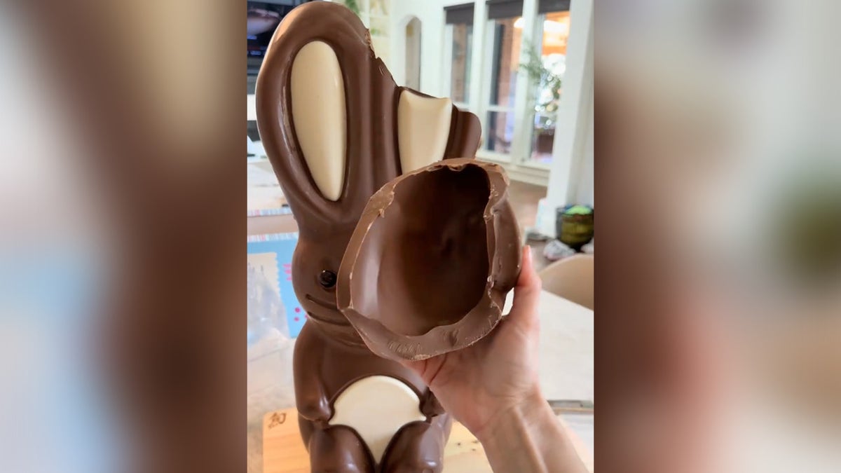 Costco content creator Laura Lamb holding sliced piece on chocolate bunny ear.