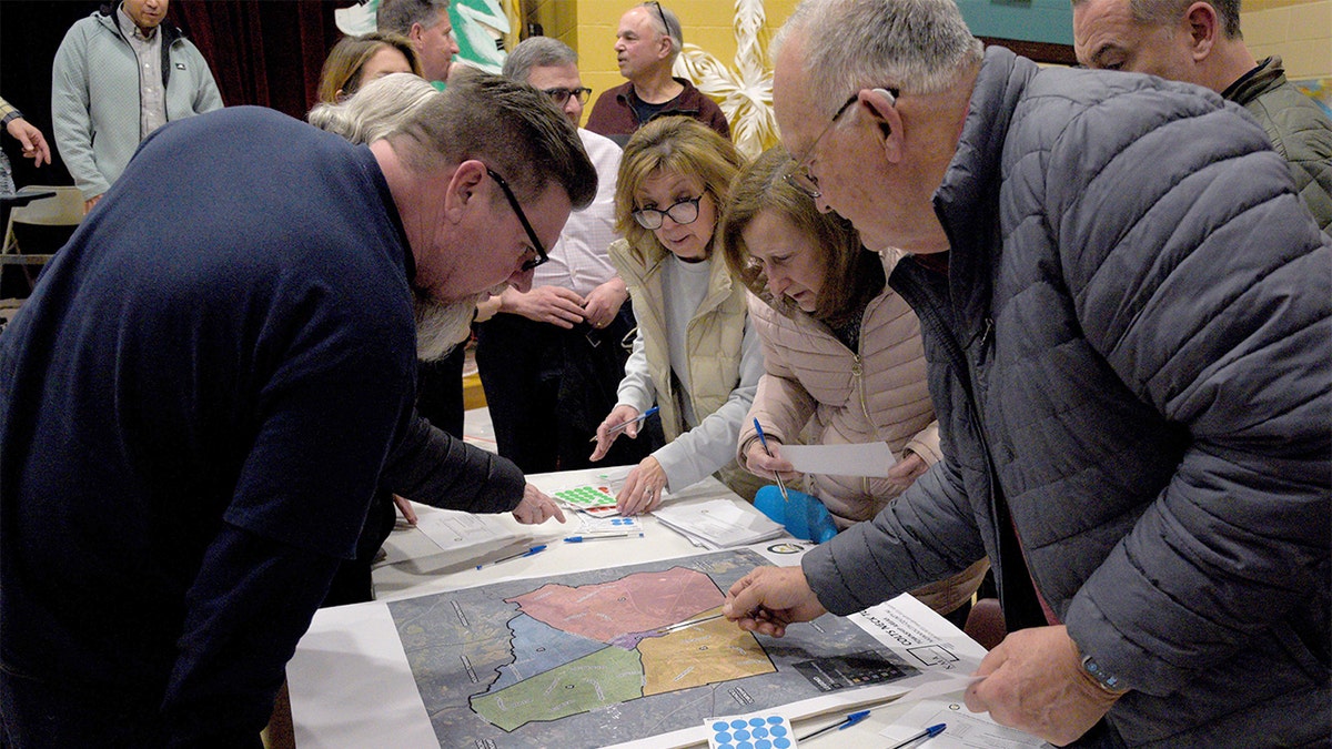 Community members review a large township map displayed inside an elementary school classroom during a public meeting in New Jersey.