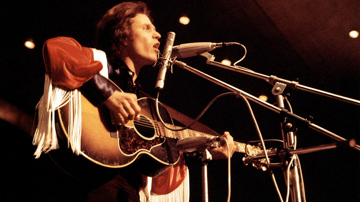 Country Joe holds guitar on stage