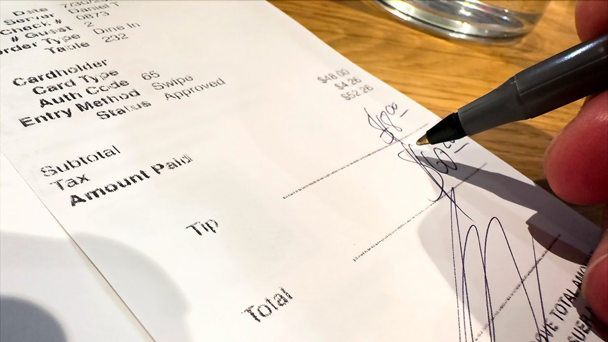 A customer leaves a tip on a restaurant receipt.