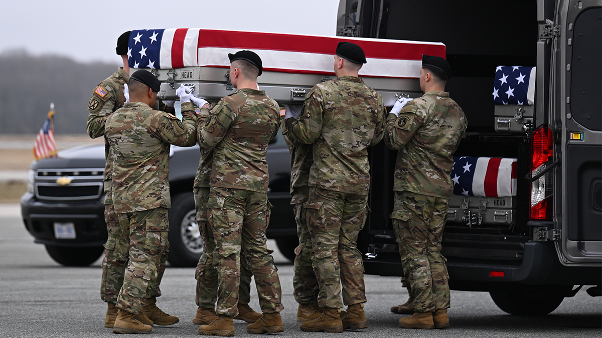 A U.S. Army carry team transports a flagged-draped transfer case to a vehicle during a dignified transfer at Dover Air Force Base