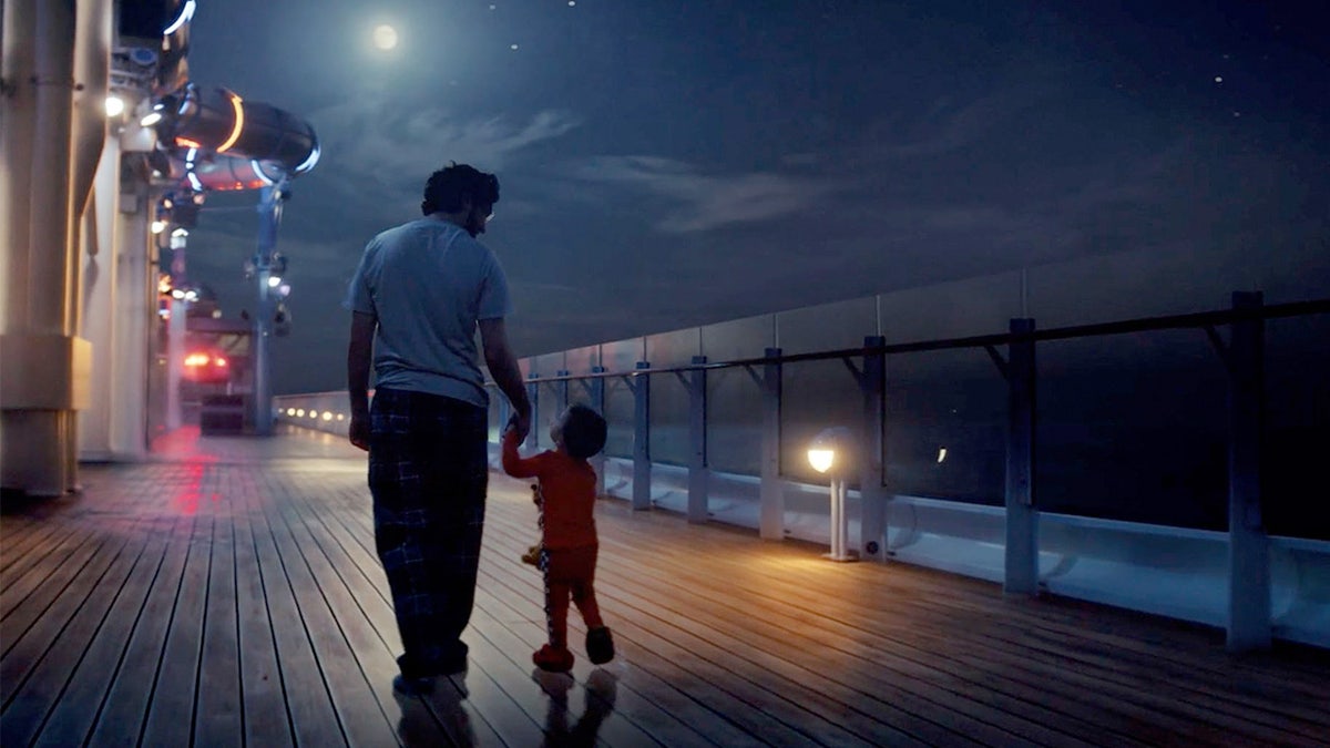 Father and son walk hand-in-hand on a Disney cruise ship