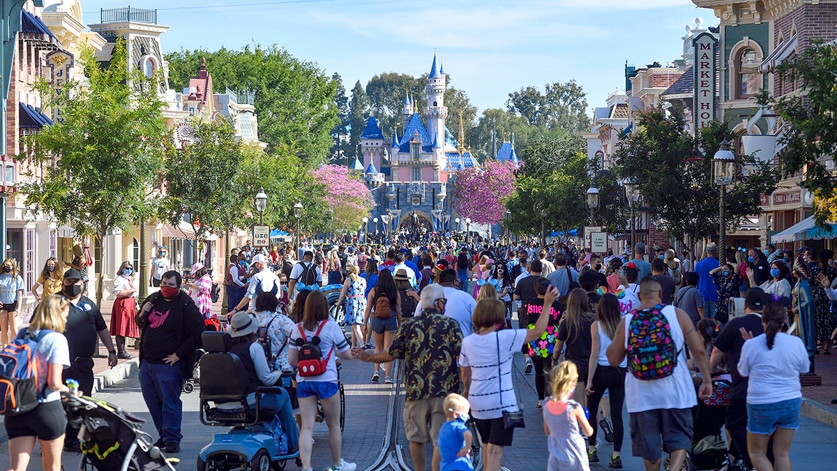 Crowds walking down Main Street, U.S.A. toward Sleeping Beauty Castle at Disneyland Park on a sunny day.
