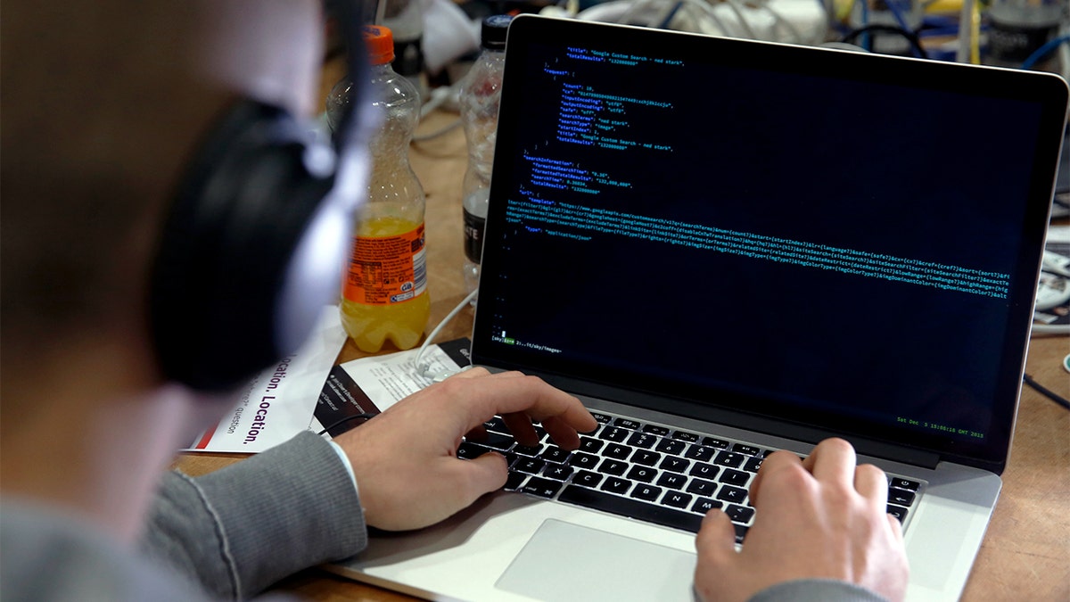 A man types code into a laptop.